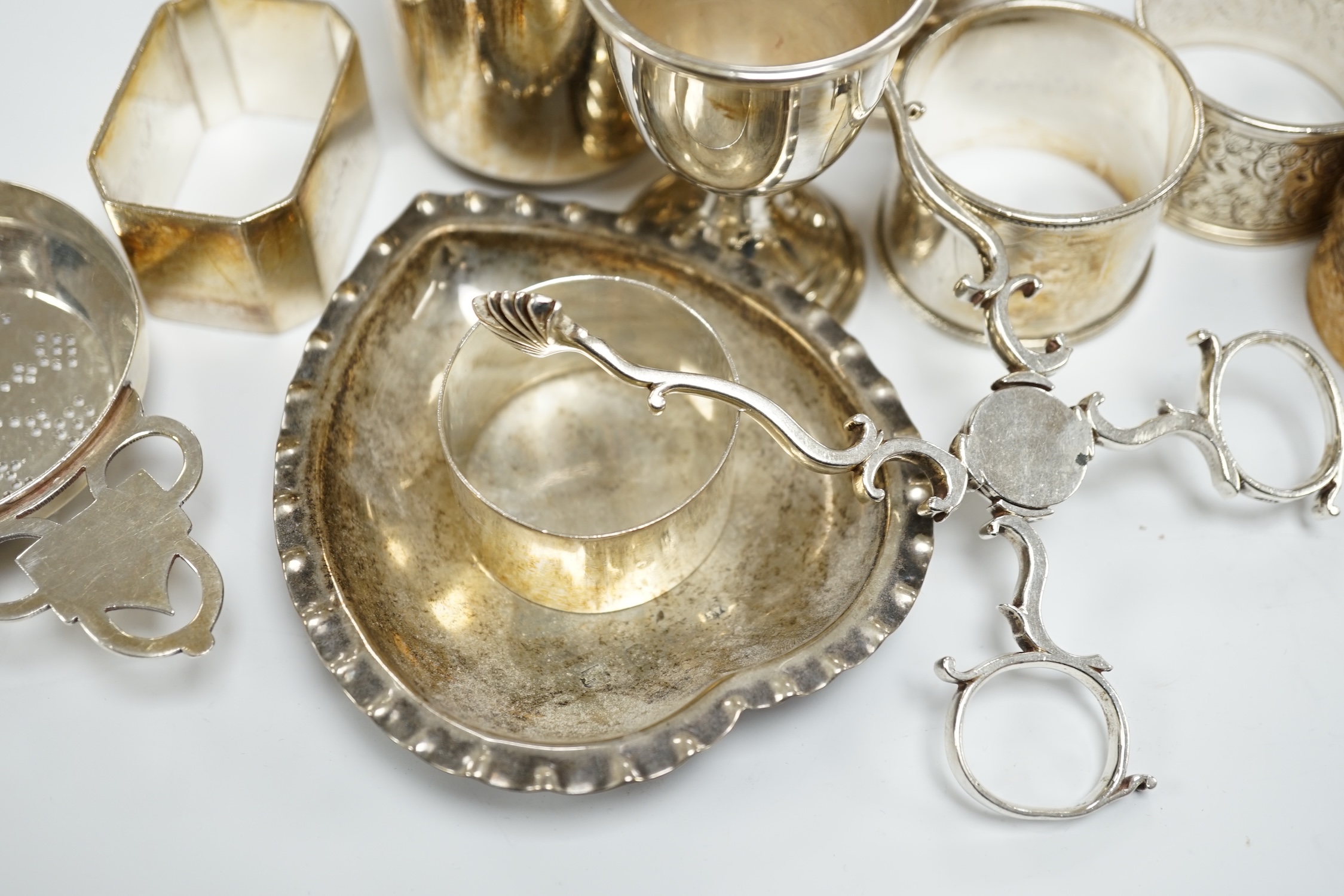 Assorted small silverwares including napkin rings, mugs, tea strainer and pair of Georgian sugar nips.